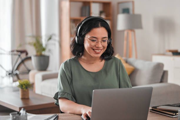 A woman is wearing headphones while using a laptop computer. - Plymouth, MN - Legacy Pro