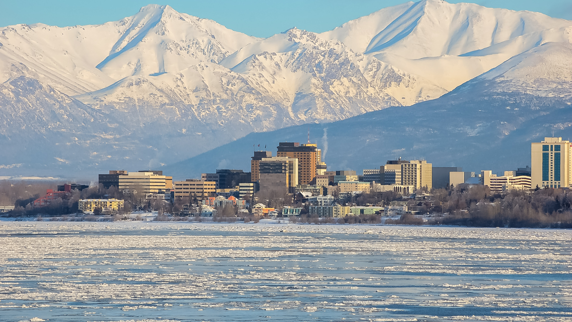 A city with mountains in the background and a body of water in the foreground