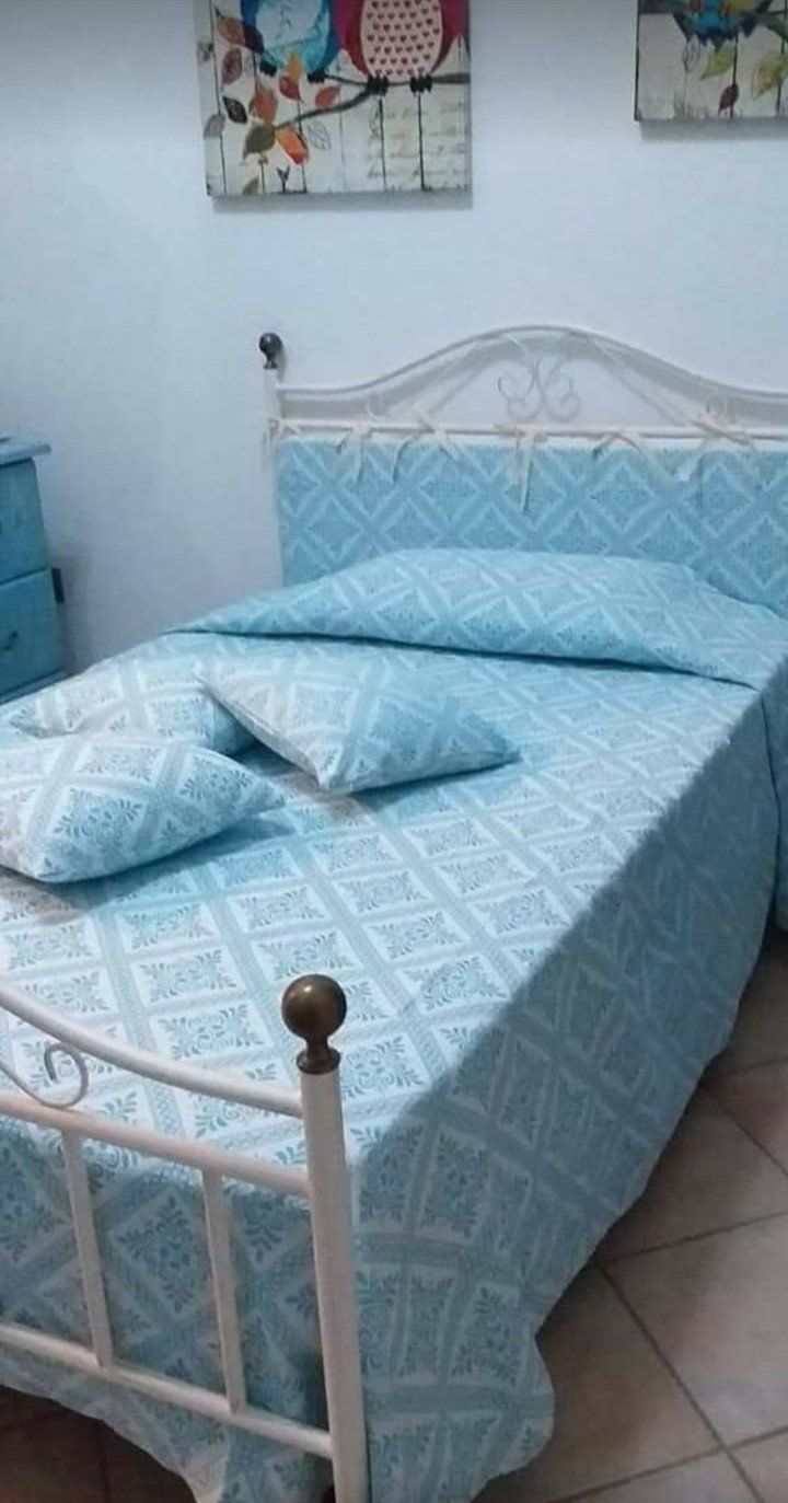 Un letto con un piumone blu e cuscini in una camera da letto.