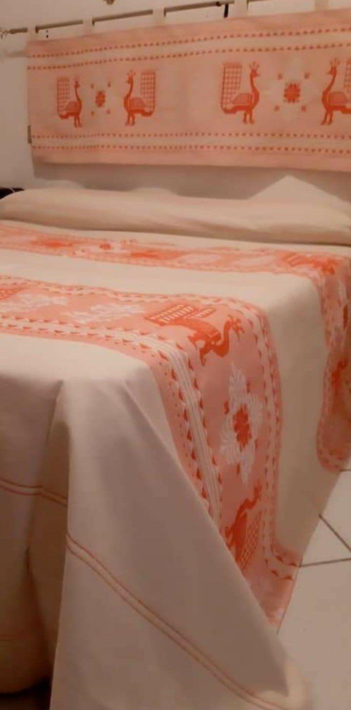 Un letto con una tovaglia rosa e bianca.