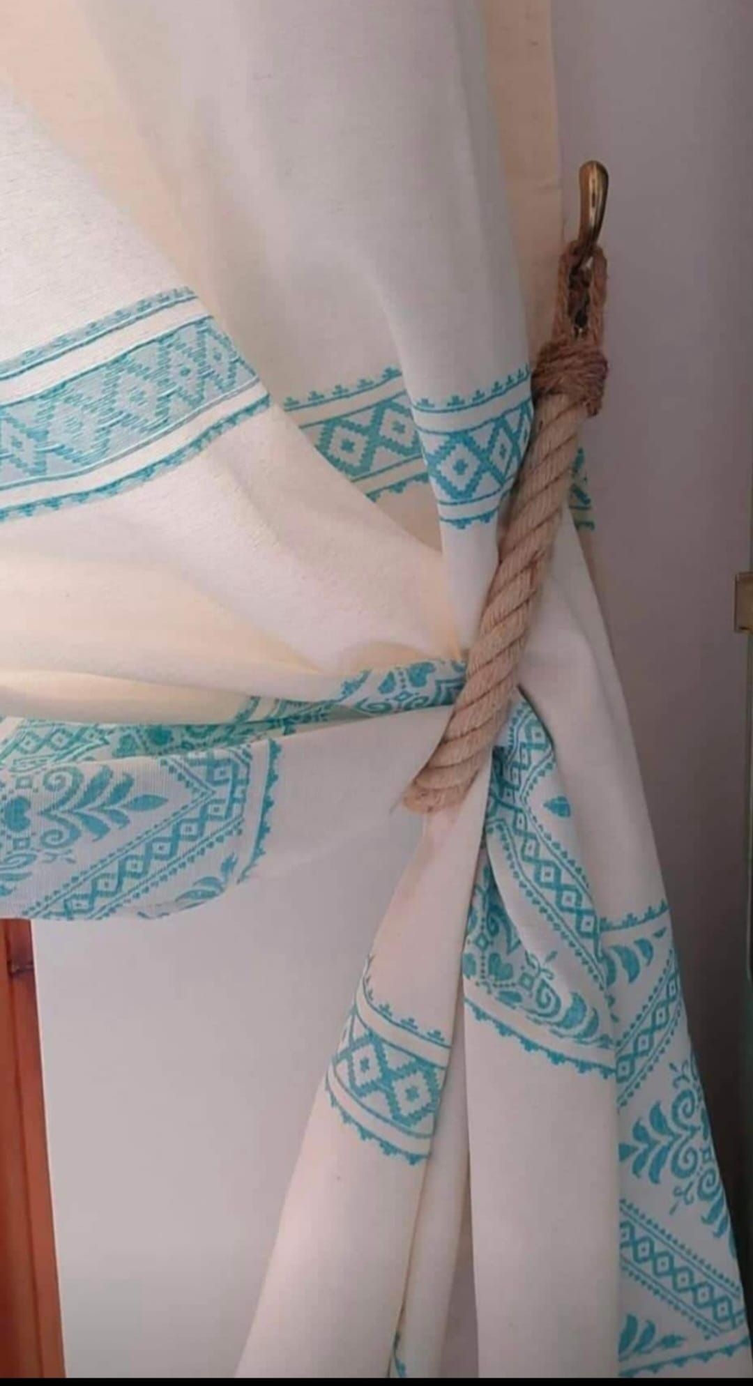 Primo piano di una tenda bianca e blu con un laccio di corda.