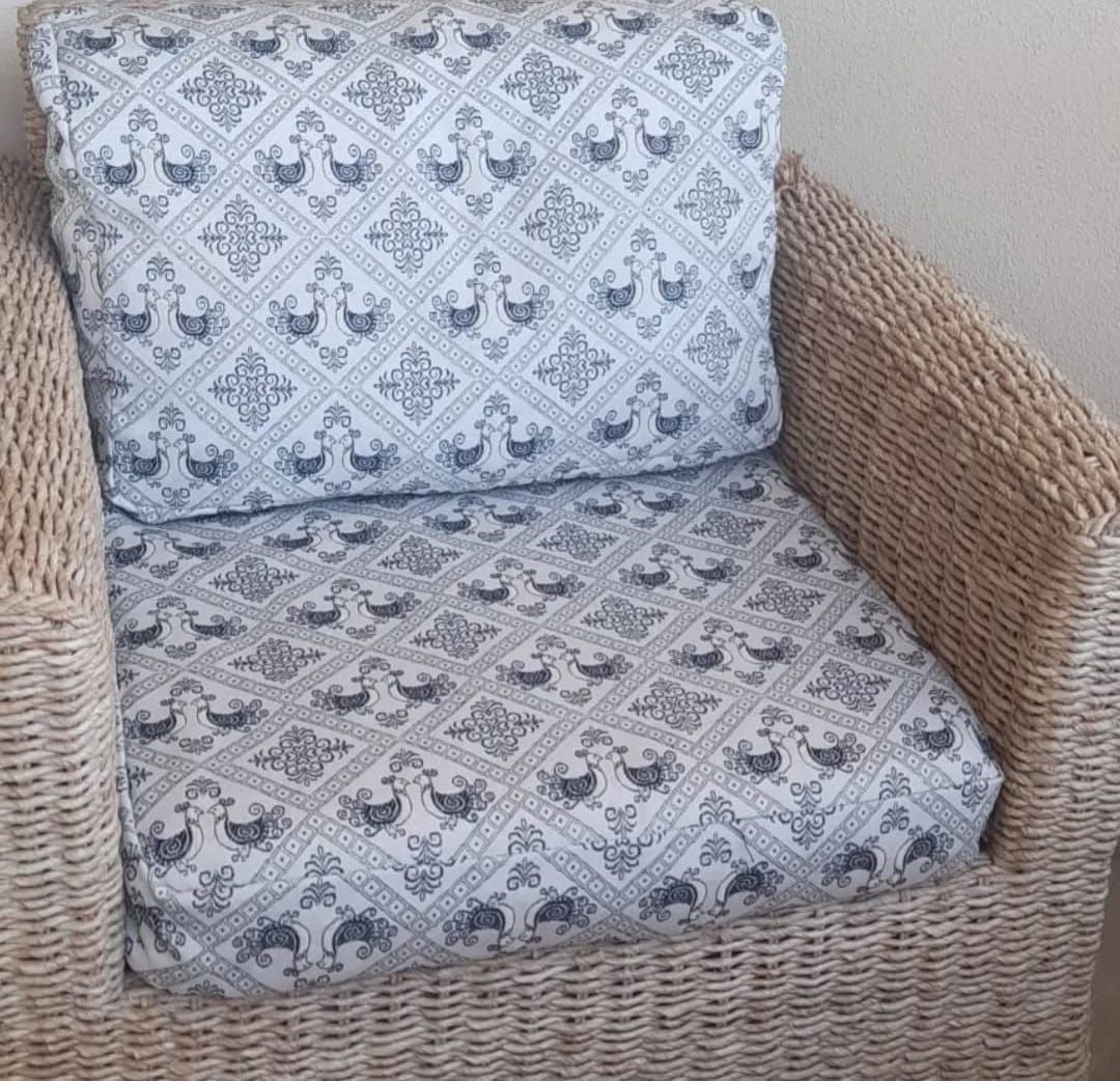 Una sedia di vimini con un cuscino decorato.