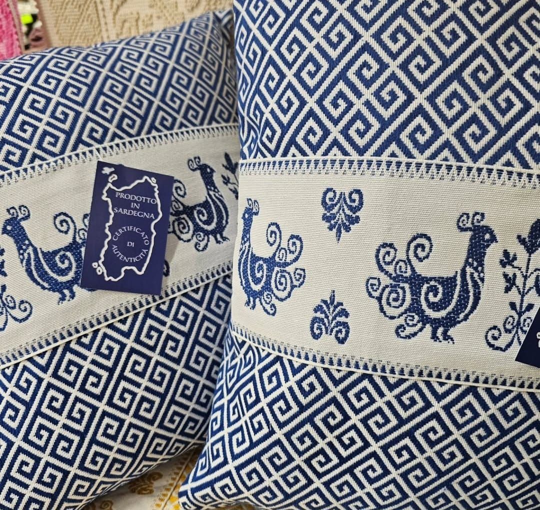 Due cuscini blu e bianchi con sopra degli uccelli sono appoggiati su un tavolo.