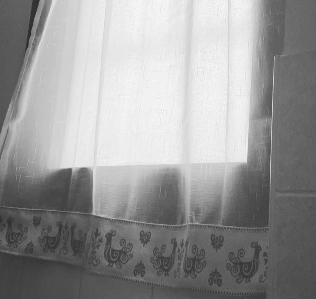 Una foto in bianco e nero di una finestra con una tenda appesa.