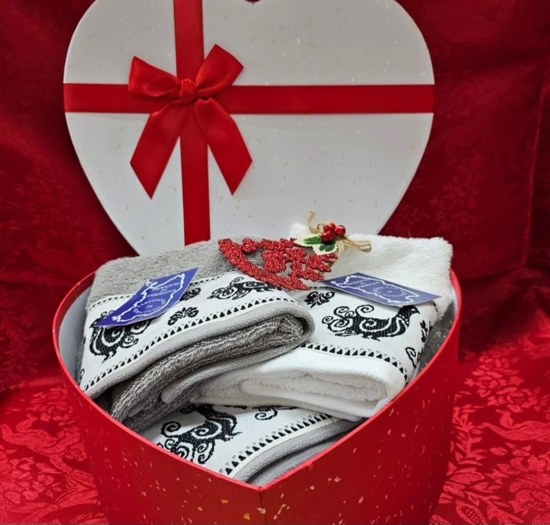 Una scatola a forma di cuore piena di asciugamani e un fiocco rosso