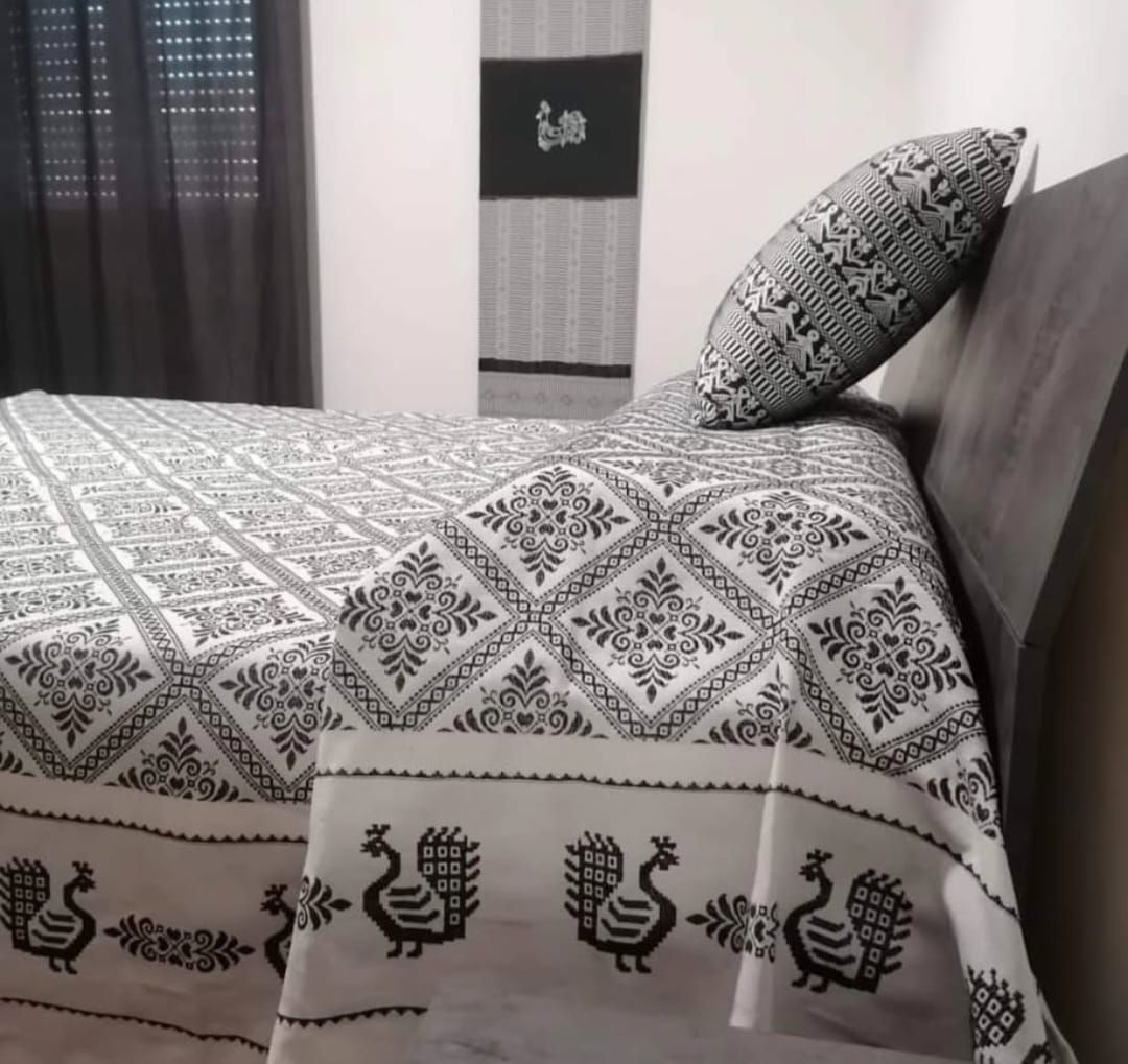 Un letto con una coperta bianca e nera con delle galline sopra