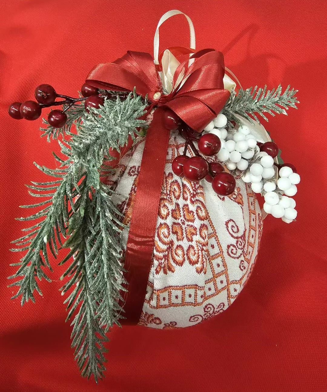 Un ornamento natalizio con un fiocco rosso e delle bacche sopra