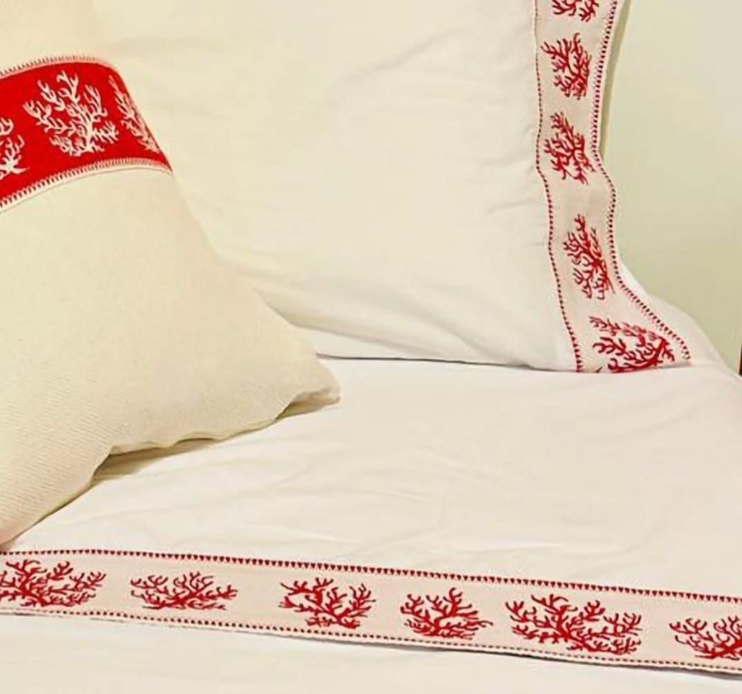 Un letto con lenzuola bianche e cuscini rossi ricamati