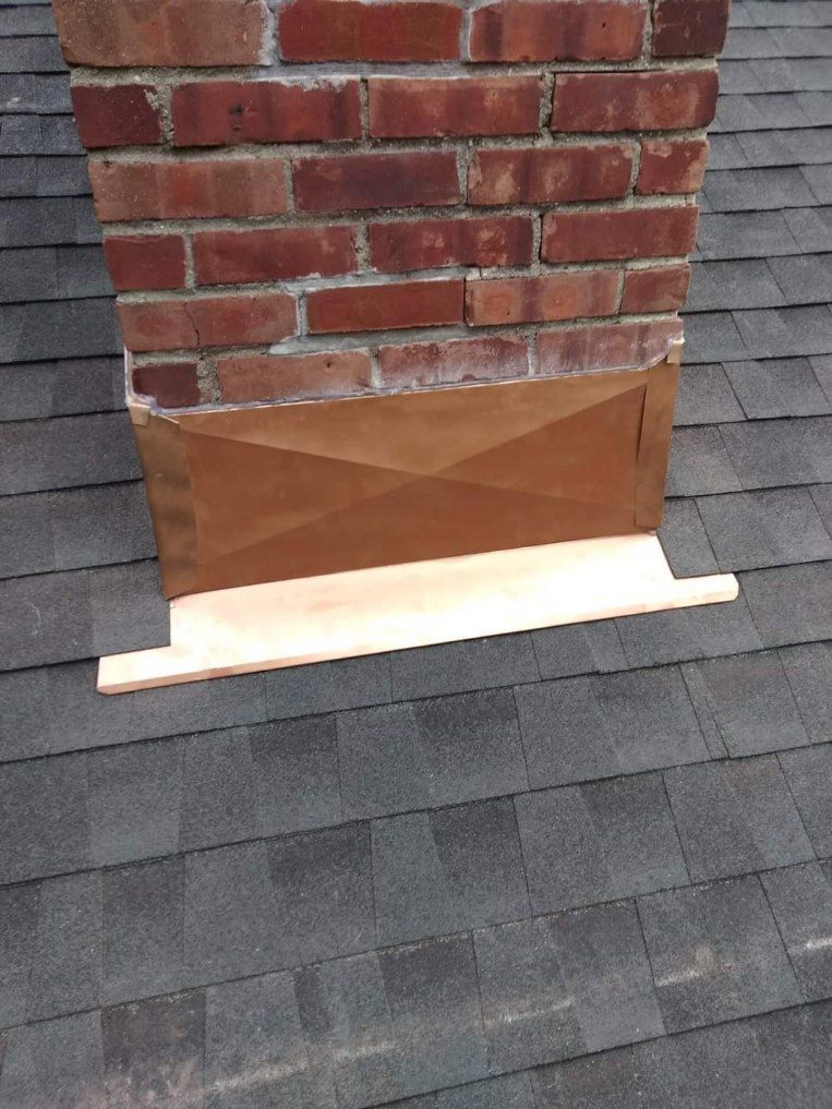 A brick chimney is sitting on top of a roof.
