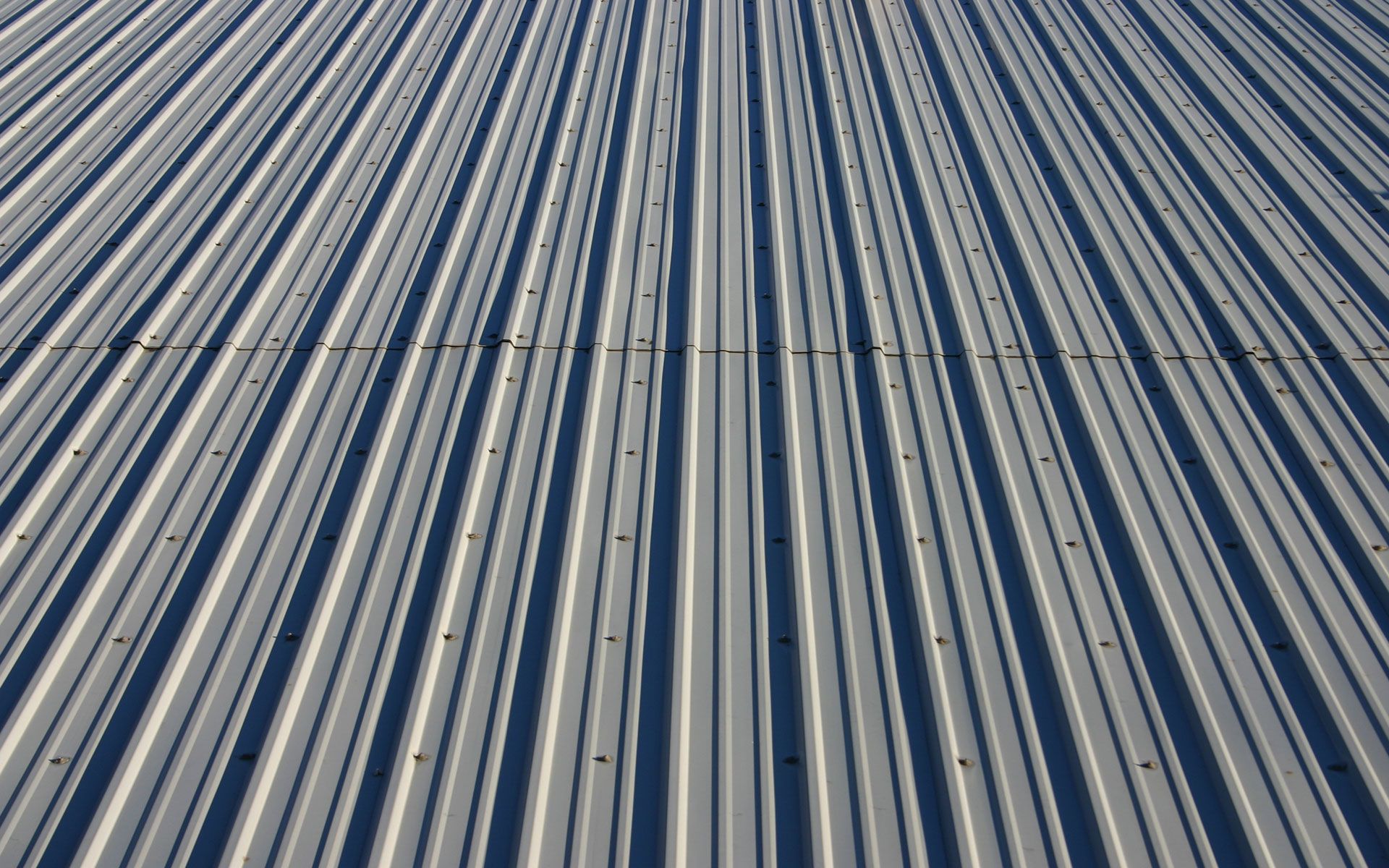 A close up of a metal roof with a blue sky in the background
