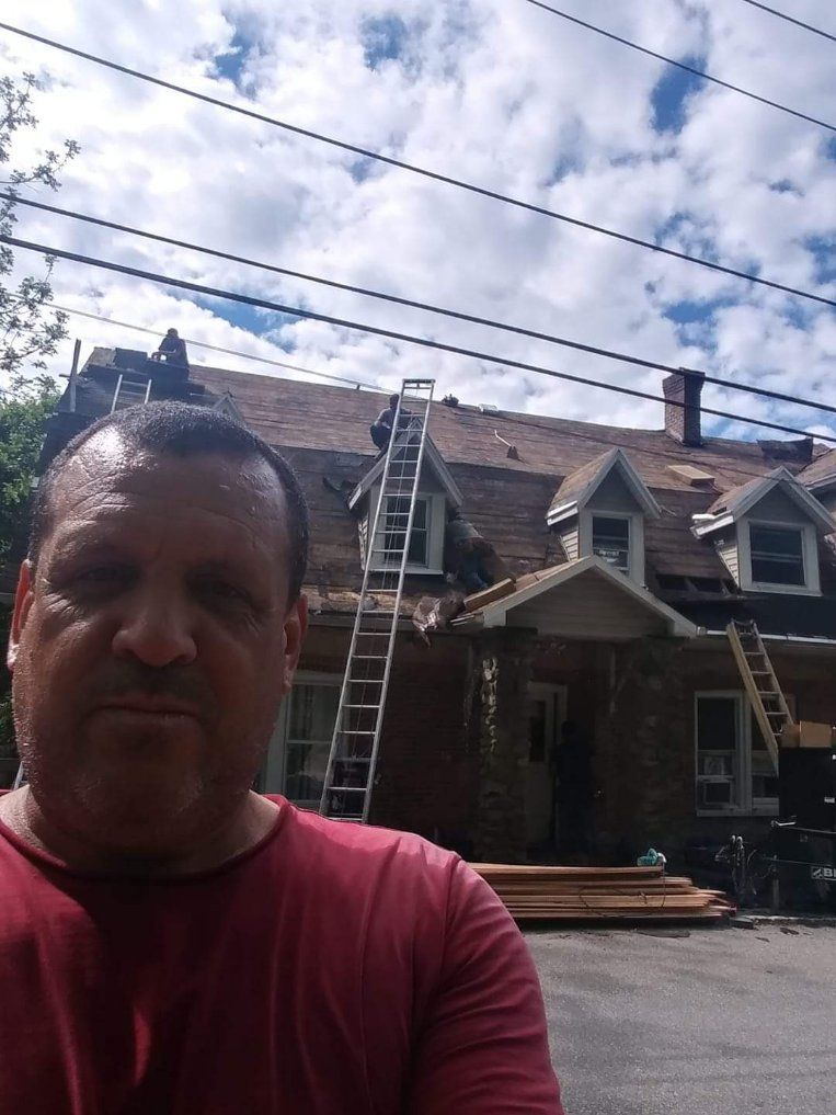 A man in a red shirt is standing in front of a house under construction