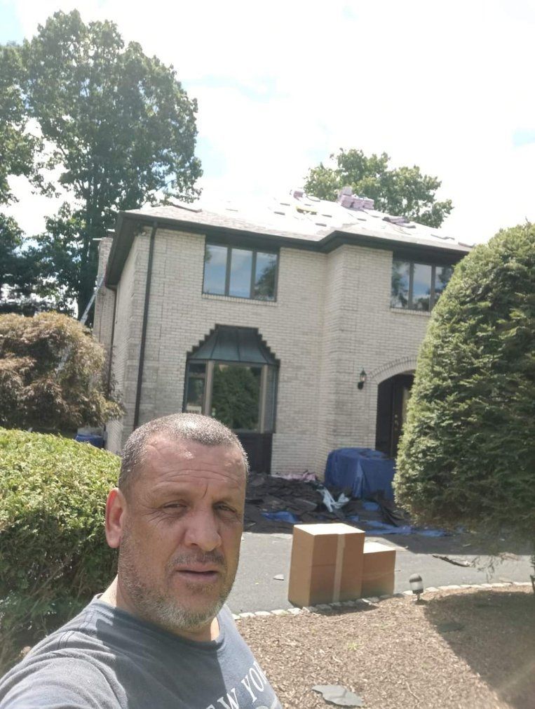 A man is taking a selfie in front of a house.