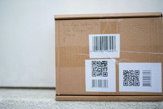 A cardboard box with barcodes on it is sitting on a doorstep.