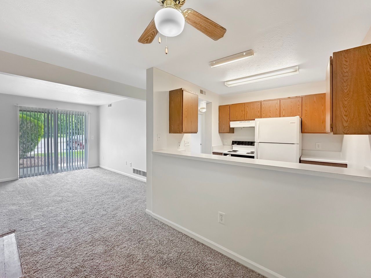 There is a ceiling fan in the kitchen and a sliding glass door in the living room.