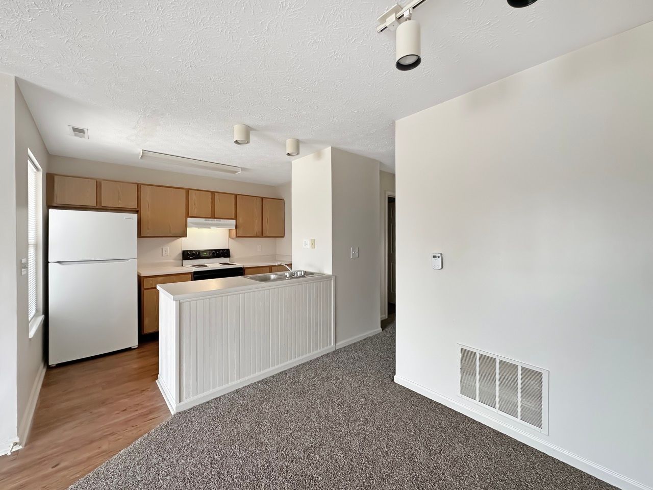 An empty apartment with a kitchen and a refrigerator