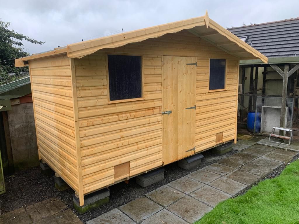 A raised 10' x 6' Apex Shed with door in middle and windows either side. Holes under the windows for the chickens to access.