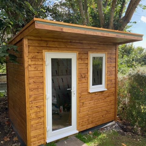 The completed 9' x 7' Garden Office in deluxe shiplap with the PVC window and door installed by customer.