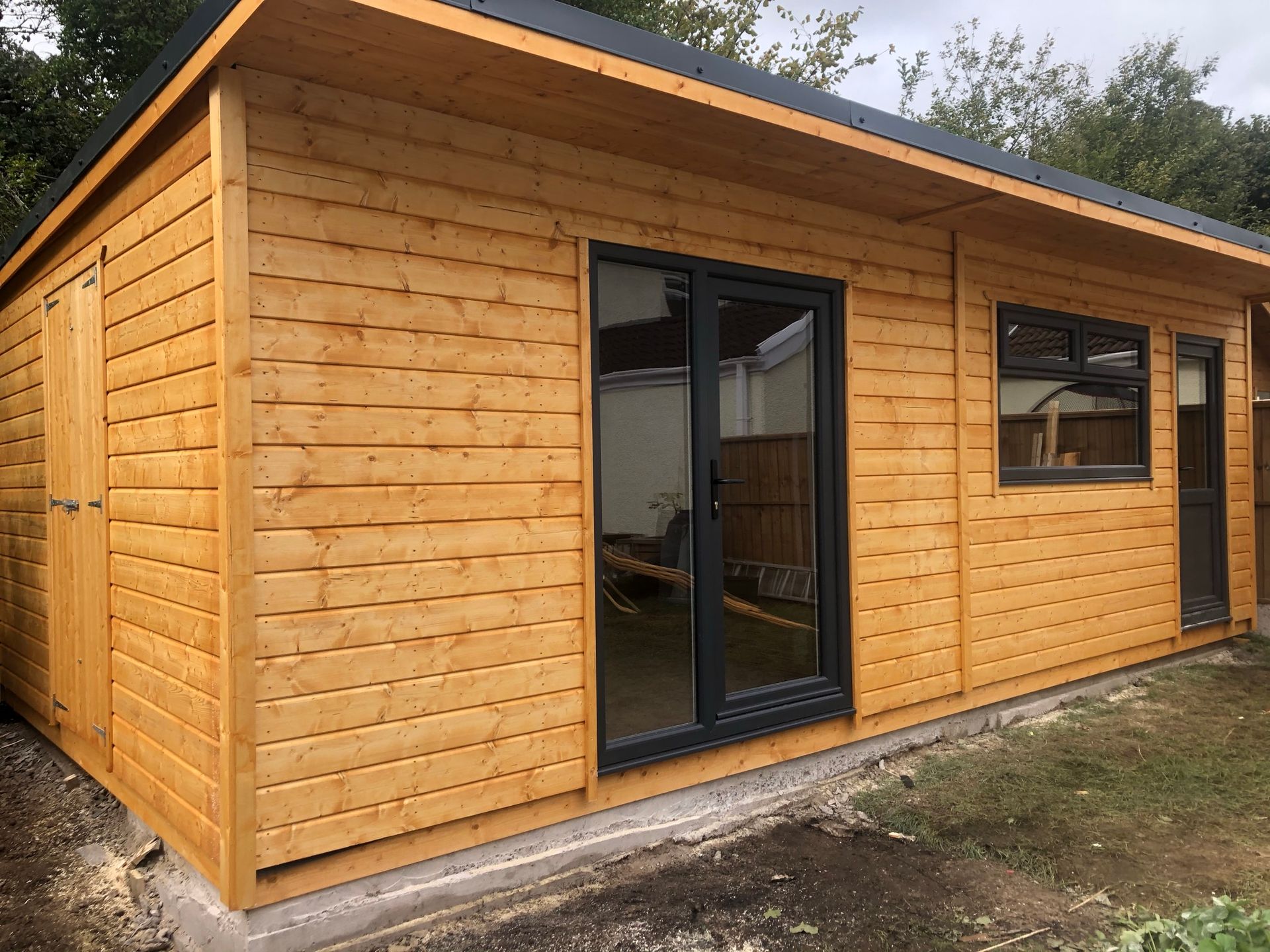 24' x 13' Workshop storage and summerhouse combined with a double door access from the side divided off by an internal division. Anthracit pvc door with single pane window on the side that's fixed. Window with two top openers then a single pvc door. half glass and half pvc.