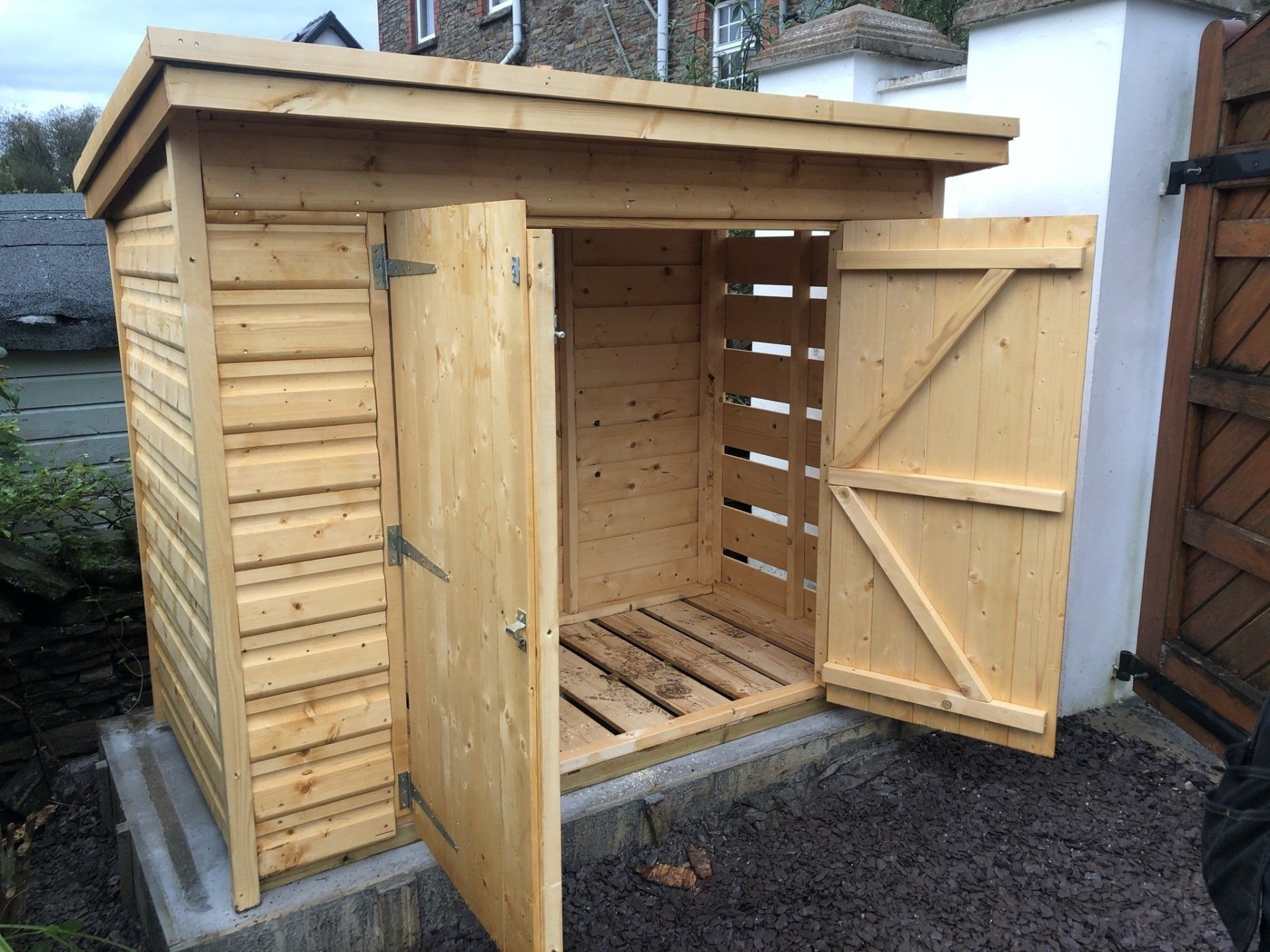 Log store with open slatted floor and side then planked on the back and other side. Double doors 