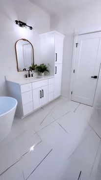 A bathroom with white cabinets , a sink , a mirror and a tub.