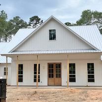 A white house with a metal roof and a porch.