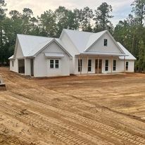 A white house is sitting on top of a dirt field.