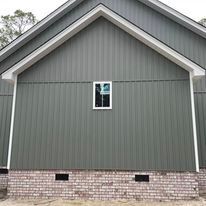 A gray house with a window on the side of it.