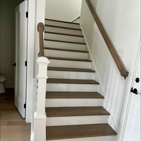 A white staircase with wooden steps and a wooden railing in a house.