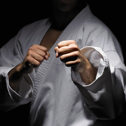 A man in a white karate uniform has a black belt around his waist