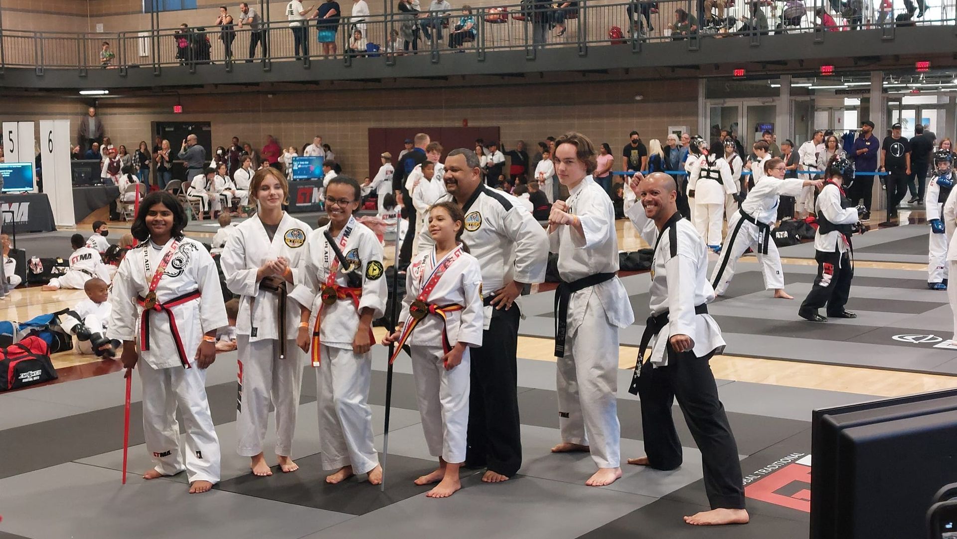 Martial arts students in white uniforms pose together at a competition.
