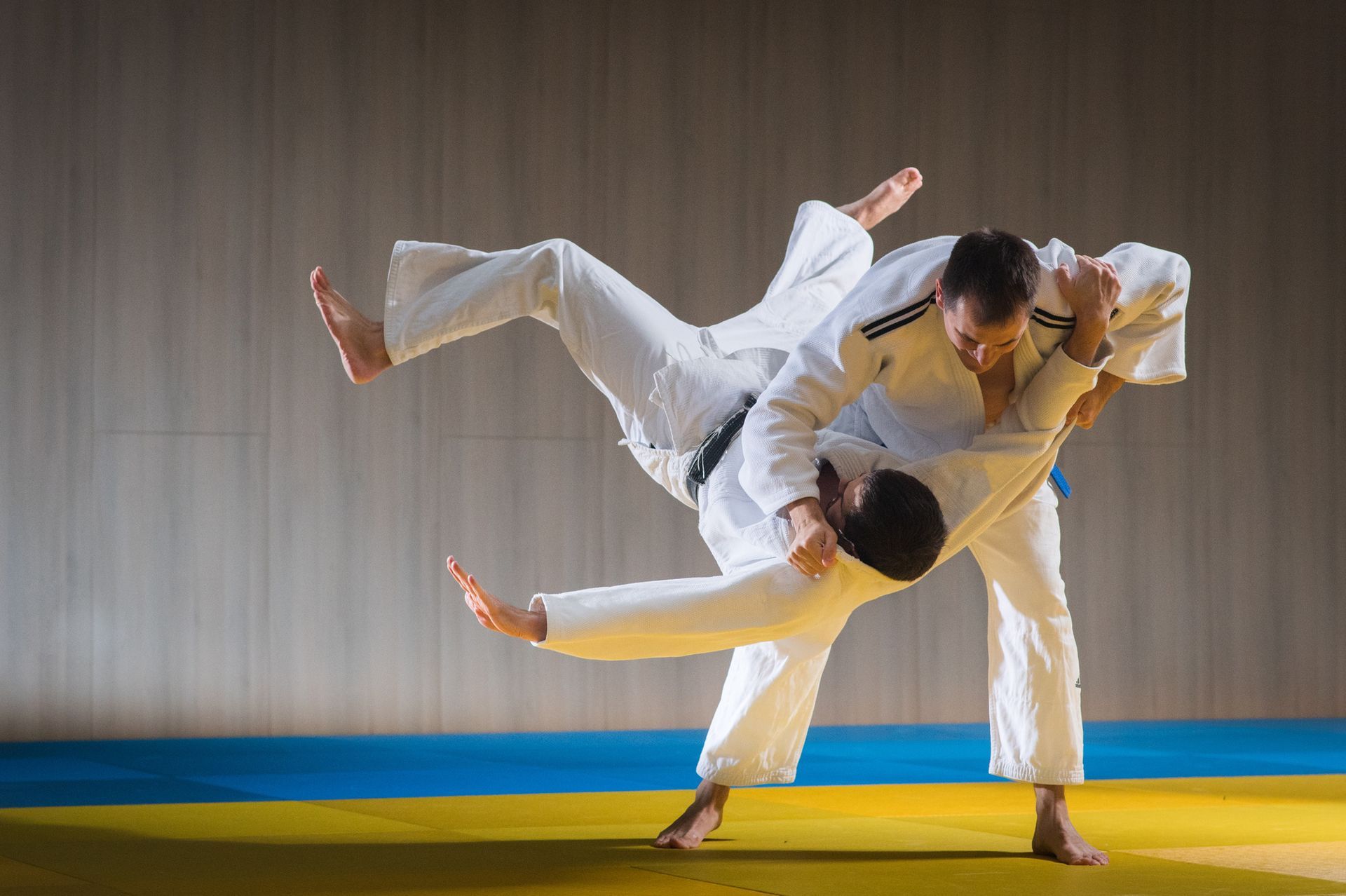 two men in white karate uniforms are practicing judo