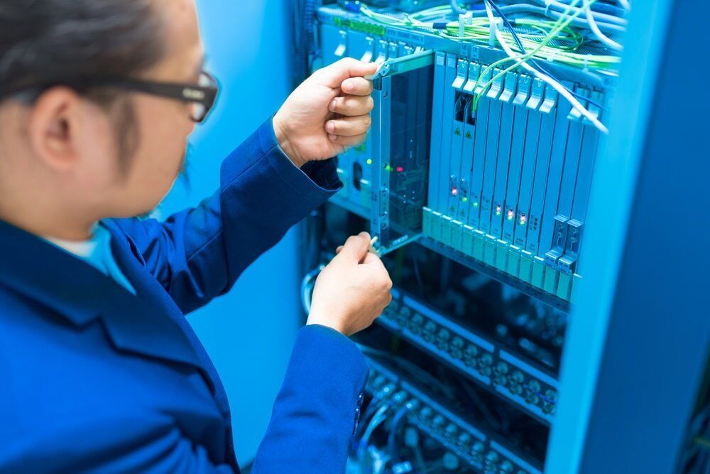 A Man In A Blue Jacket Is Working On A Server — Black Label I.T. in Garbutt, QLD