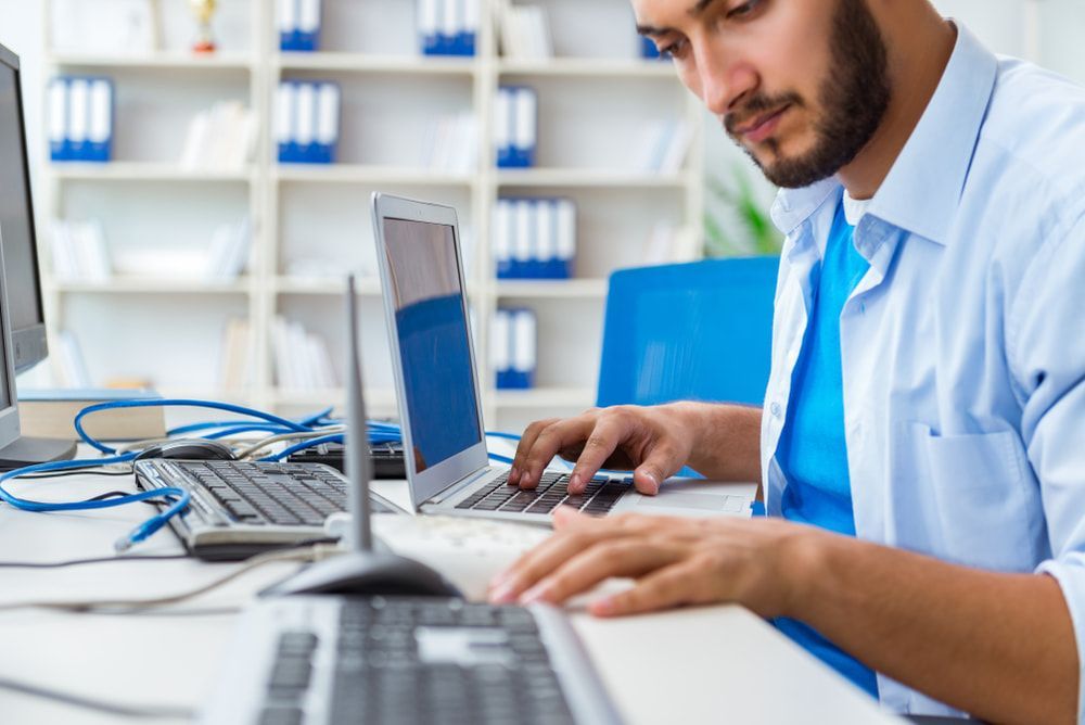 A Man Is Sitting At A Desk Using A Laptop Computer — Black Label I.T. in Garbutt, QLD