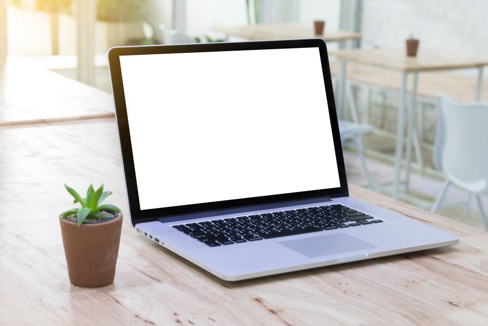 A Laptop With A White Screen Is Sitting On A Wooden Table Next To A Potted Plant — Black Label I.T. in Garbutt, QLD