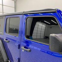 A blue jeep wrangler is parked in a garage.