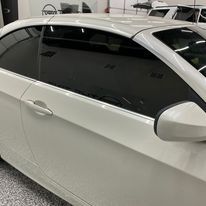 A white car with black windows is parked in a garage.