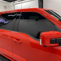 A red ford f150 truck is parked in a garage.