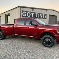 A red truck is parked in front of a building that says `` got tint ''.
