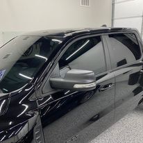 A black truck is parked in a garage next to a garage door.