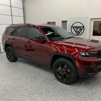 A red jeep grand cherokee is parked in a garage.