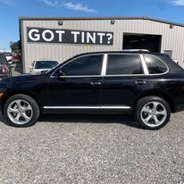 A black suv is parked in front of a building that says `` got tint ''.