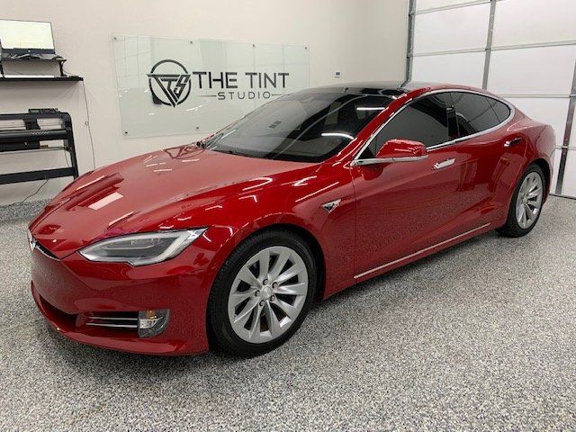 A red tesla model s is parked in a garage.