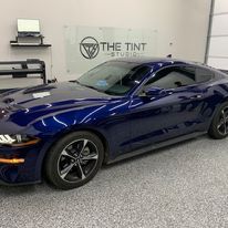 A blue mustang is parked in a garage.
