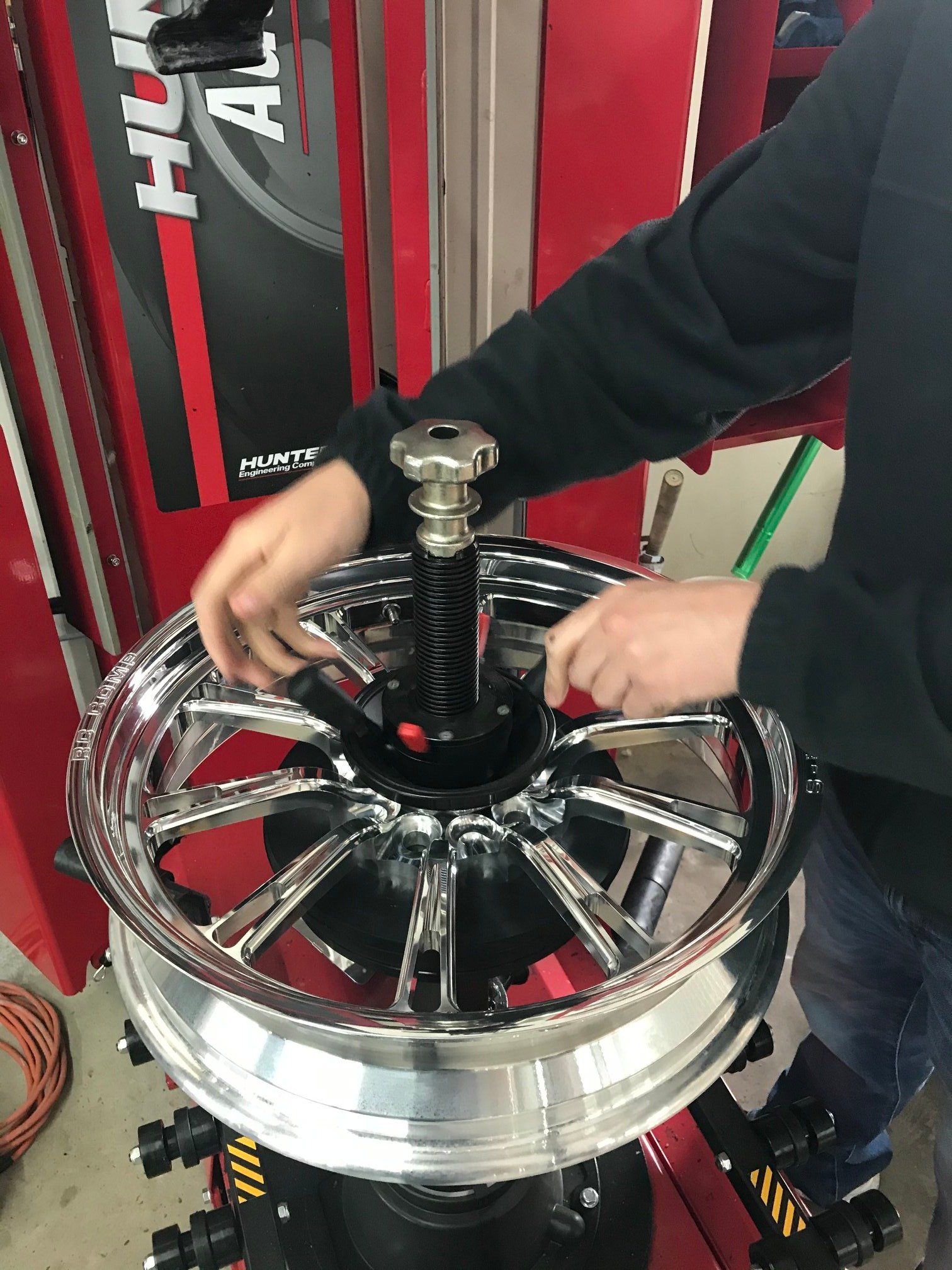 A person is working on a motorcycle wheel on a machine.