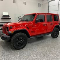 A red jeep wrangler is parked in a garage.