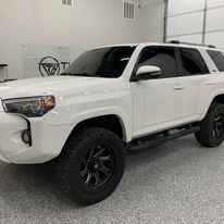 A white toyota 4runner is parked in a garage.
