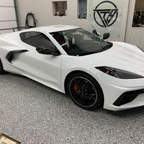 A white sports car is parked in a garage.