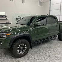 A green truck is parked in a garage.