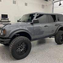 A gray ford bronco is parked in a garage.