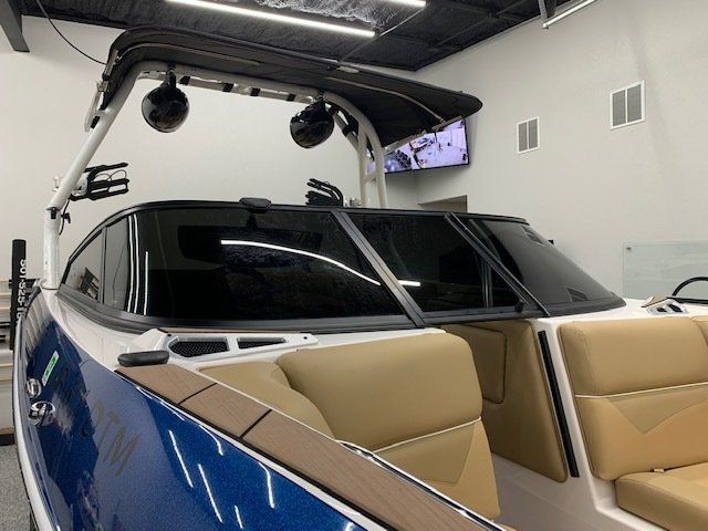 A blue and white boat with tan seats is parked in a room.